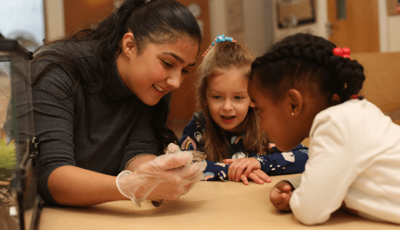 Teacher showing two girls a lizard