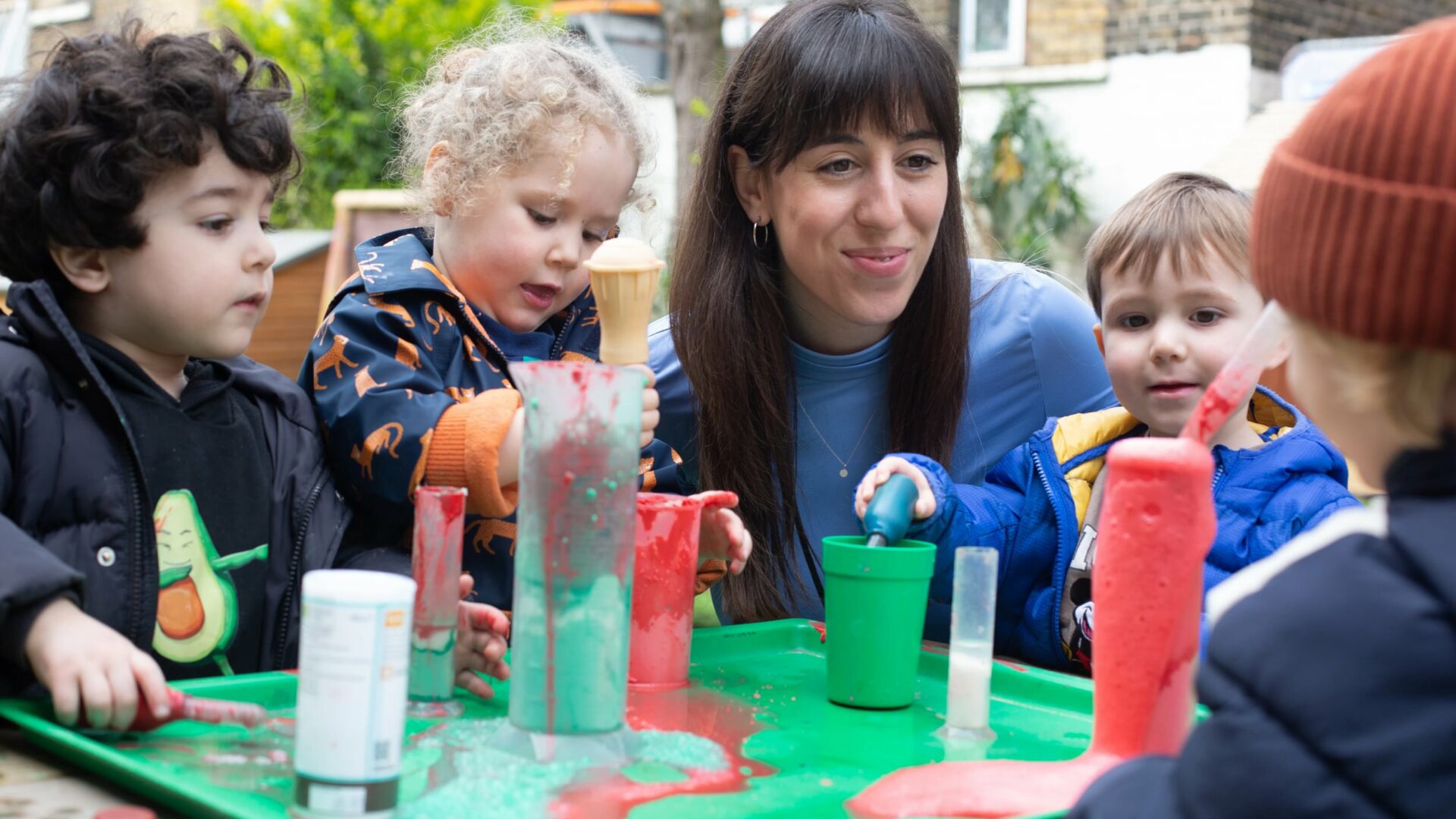 Staff member and children doing a science experiment outdoors